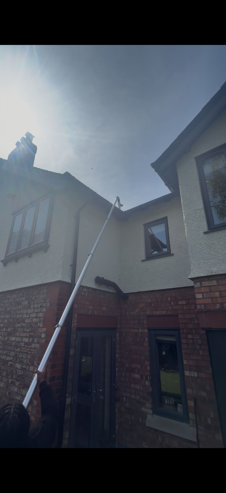 A telescopic gutter-vac pole reaching up to a two-storey gutter